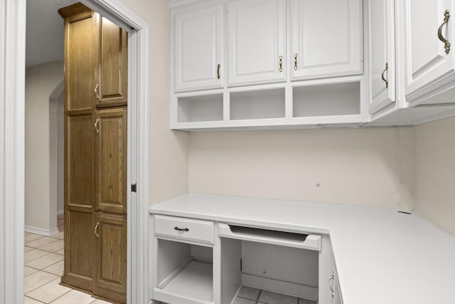 unfurnished office featuring built in desk and light tile patterned flooring