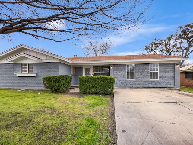 ranch-style house with driveway, brick siding, board and batten siding, and a front yard