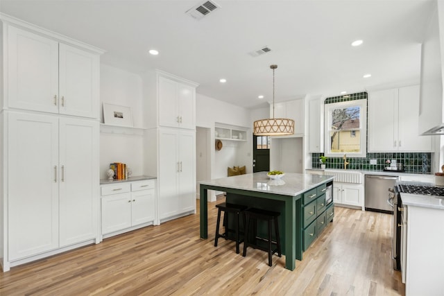 kitchen featuring white cabinetry, a center island, stainless steel dishwasher, and decorative light fixtures