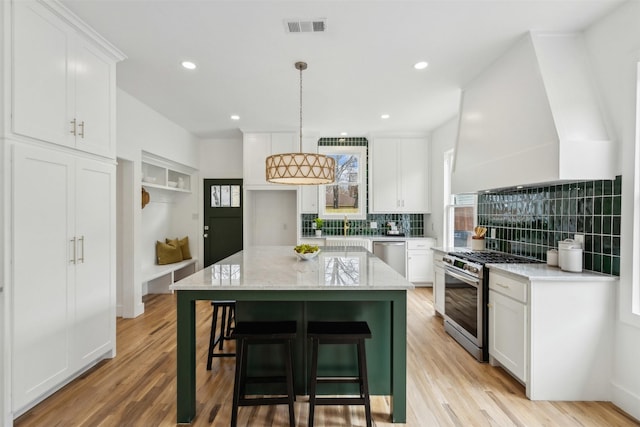 kitchen with pendant lighting, a breakfast bar area, white cabinetry, stainless steel appliances, and a center island