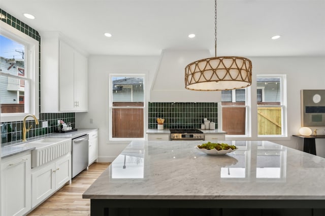 kitchen featuring pendant lighting, white cabinetry, sink, stainless steel appliances, and custom range hood