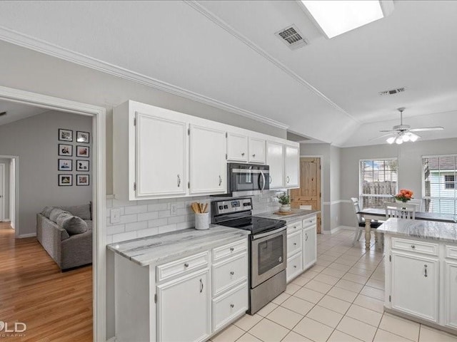 kitchen featuring white cabinetry, tasteful backsplash, lofted ceiling with skylight, and appliances with stainless steel finishes