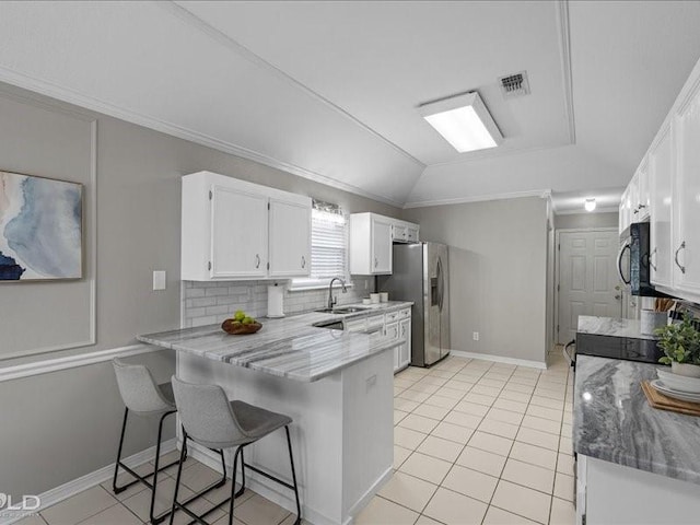 kitchen with sink, a breakfast bar area, appliances with stainless steel finishes, white cabinetry, and kitchen peninsula