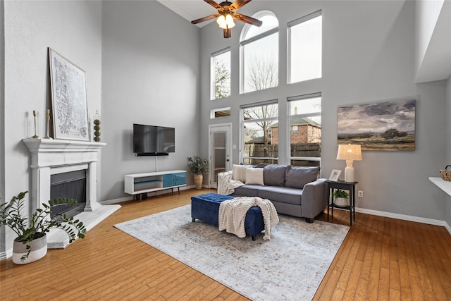 living room with a towering ceiling, ceiling fan, and light hardwood / wood-style flooring