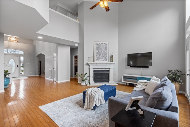 living room with wood-type flooring, a towering ceiling, and ceiling fan