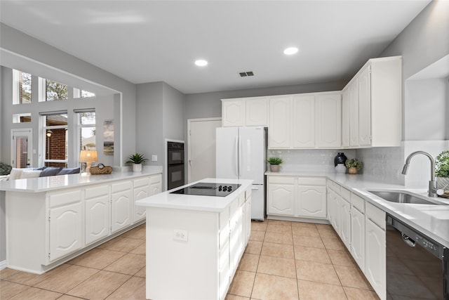 kitchen with sink, black appliances, a center island, light tile patterned floors, and white cabinets