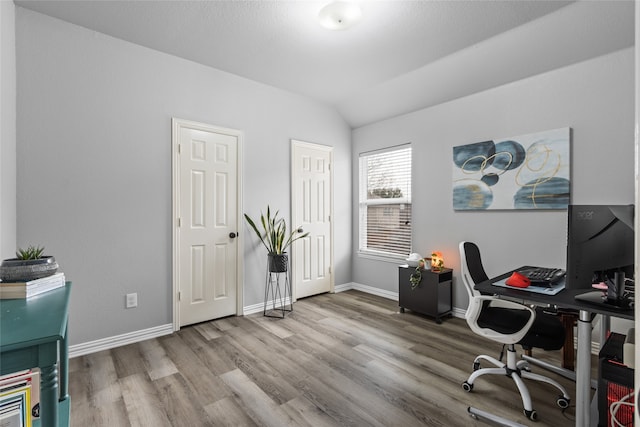 office with vaulted ceiling and light wood-type flooring