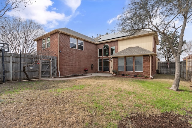 rear view of house featuring a lawn and solar panels