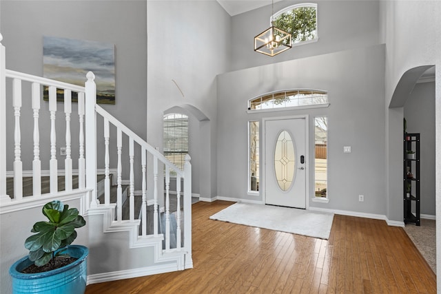 foyer entrance with an inviting chandelier, a towering ceiling, and wood-type flooring