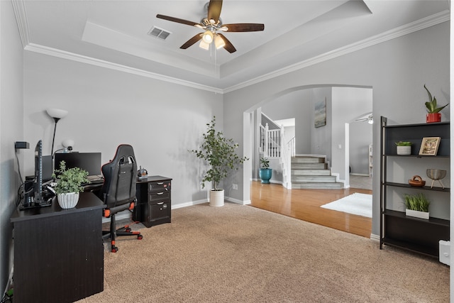 carpeted office featuring a tray ceiling, ornamental molding, and ceiling fan