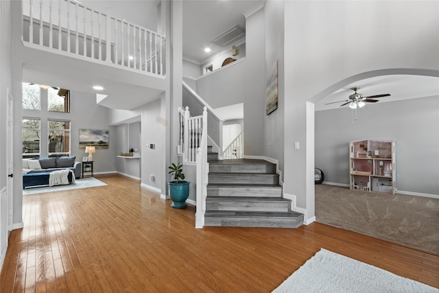 foyer with ceiling fan, a towering ceiling, and hardwood / wood-style floors