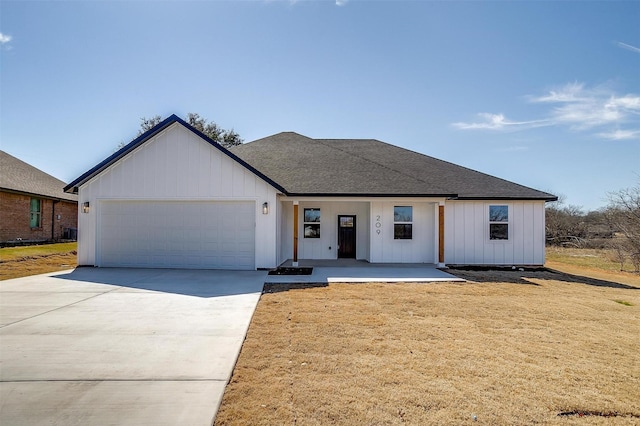 modern farmhouse featuring a garage, driveway, roof with shingles, a front lawn, and board and batten siding