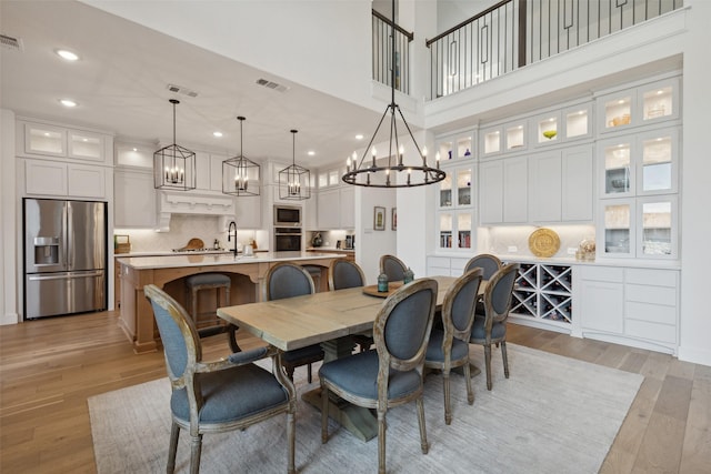 dining space featuring an inviting chandelier, light wood-style flooring, and visible vents