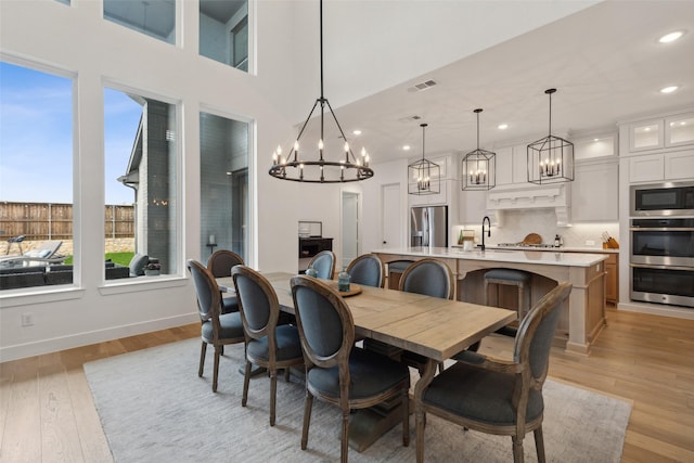 dining room featuring recessed lighting, light wood-style flooring, a chandelier, baseboards, and visible vents