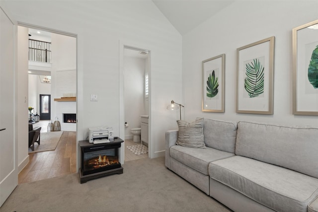 carpeted living room featuring an inviting chandelier, a fireplace, and high vaulted ceiling