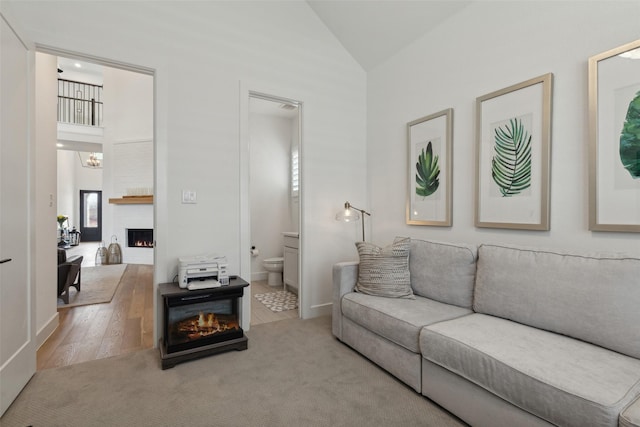 carpeted living area featuring high vaulted ceiling, a notable chandelier, and a large fireplace