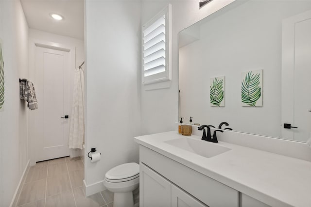 bathroom featuring toilet, tile patterned flooring, vanity, and baseboards