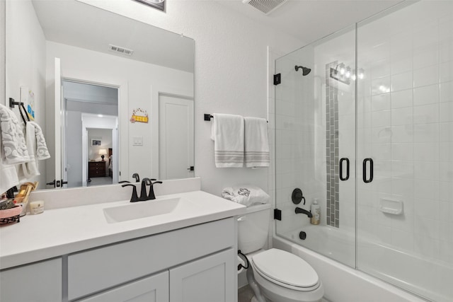 bathroom with combined bath / shower with glass door, visible vents, toilet, and vanity