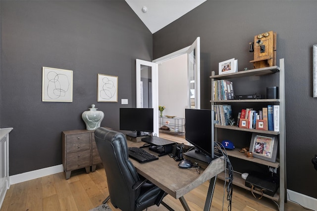 office featuring lofted ceiling, wood finished floors, and baseboards