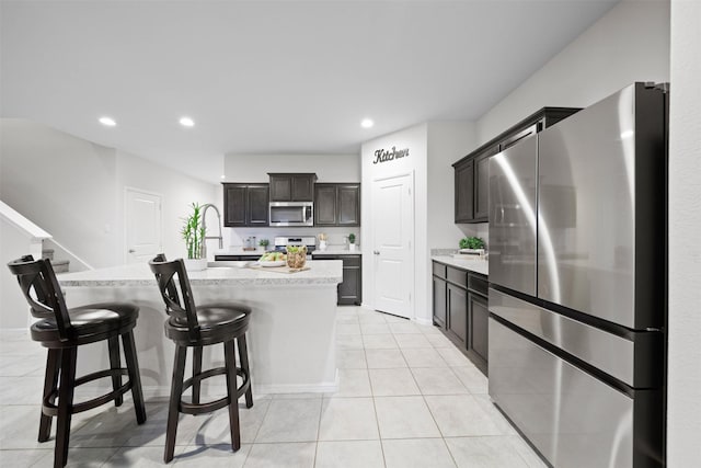 16501 Portage St, Justin, TX 76247 - kitchen featuring appliances with stainless steel finishes, light tile patterned floors, a breakfast bar area, a center island with sink, and recessed lighting