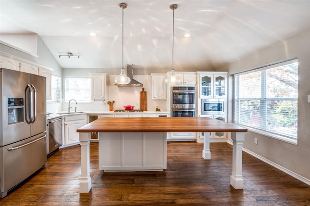 kitchen featuring a kitchen island, appliances with stainless steel finishes, white cabinets, wooden counters, and hanging light fixtures