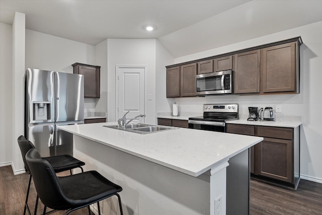 kitchen featuring dark wood-type flooring, stainless steel appliances, a kitchen island with sink, and sink