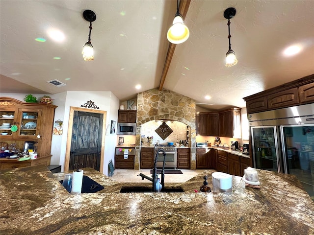 kitchen with decorative light fixtures, vaulted ceiling with beams, sink, high end appliances, and dark brown cabinetry