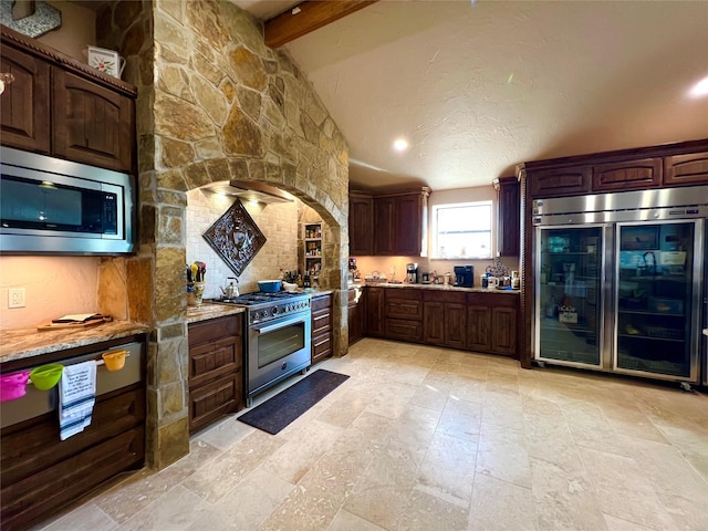 kitchen featuring built in appliances, light stone counters, dark brown cabinets, and lofted ceiling with beams