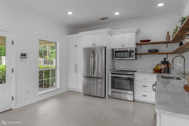 kitchen with ornamental molding, appliances with stainless steel finishes, sink, and white cabinets