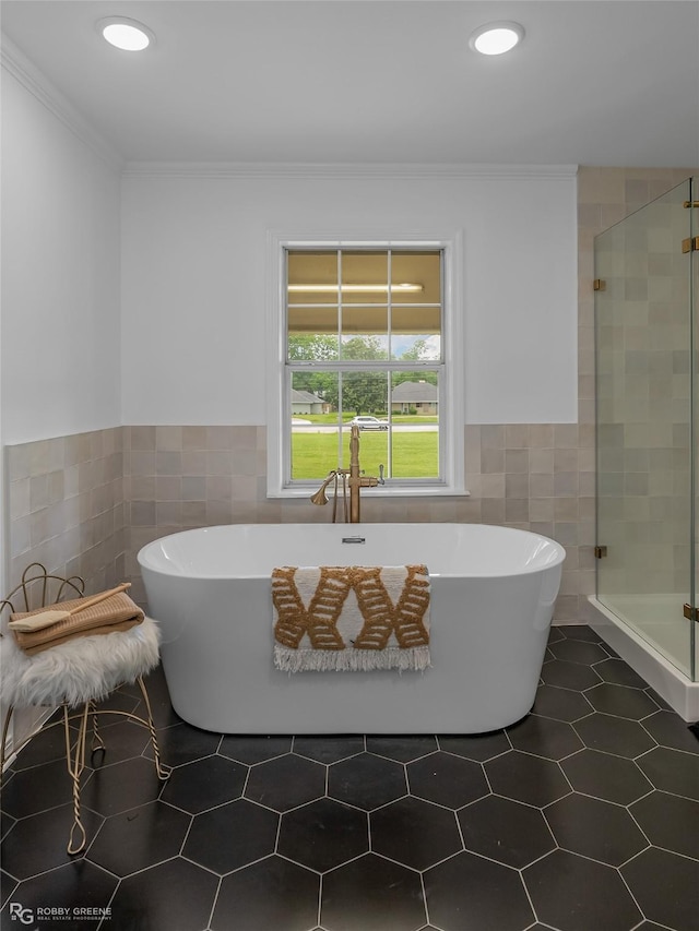 bathroom with tile patterned floors, ornamental molding, shower with separate bathtub, and tile walls