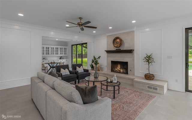 living room featuring crown molding, ceiling fan, and a high end fireplace