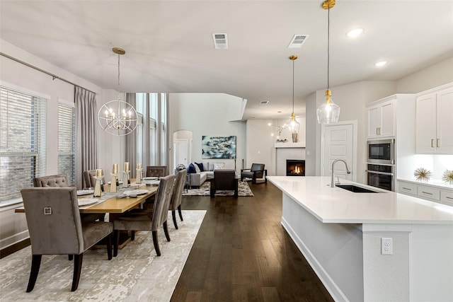 dining room featuring dark wood-type flooring, sink, and a notable chandelier