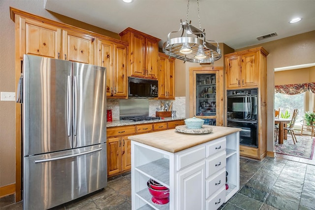 kitchen with butcher block countertops, tasteful backsplash, white cabinets, a center island, and black appliances