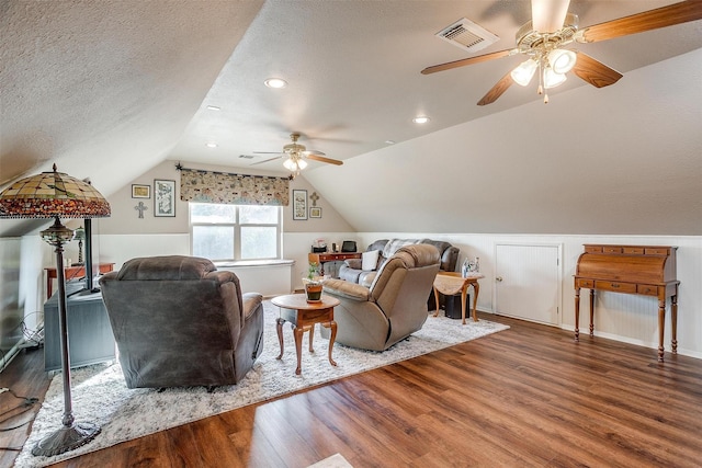 living room featuring wood-type flooring, lofted ceiling, ceiling fan, and a textured ceiling