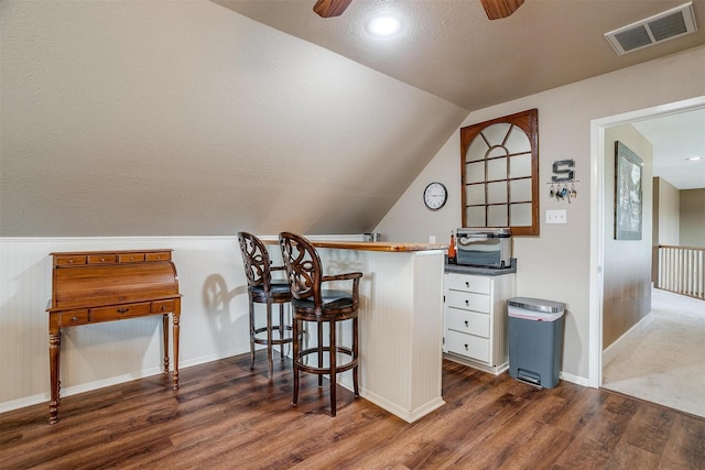 bar with lofted ceiling, dark wood-type flooring, ceiling fan, white cabinets, and a textured ceiling