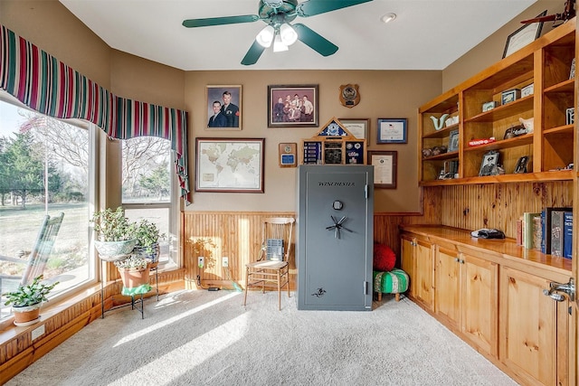 interior space with ceiling fan, light carpet, and wood walls