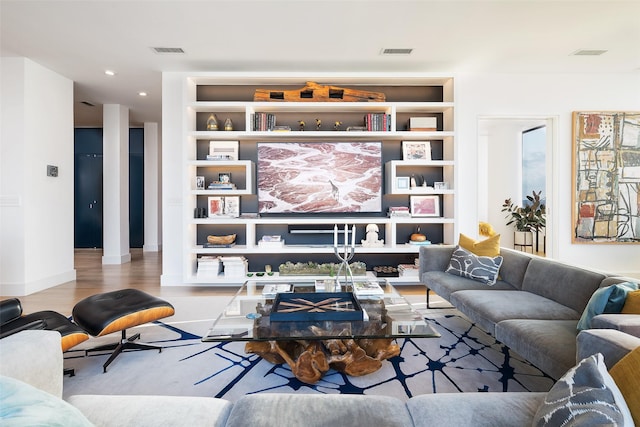 living room featuring built in shelves and light hardwood / wood-style flooring