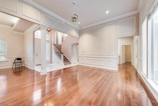 interior space featuring decorative columns, crown molding, ceiling fan, and light wood-type flooring