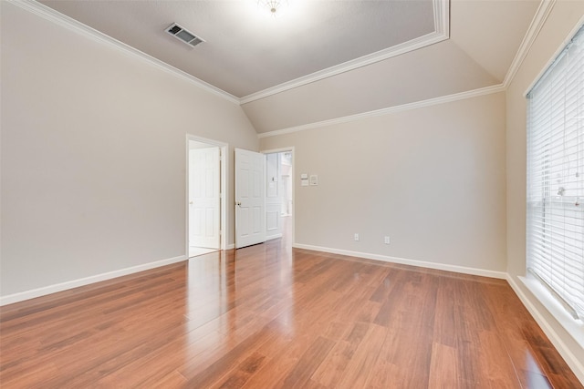 empty room with crown molding, vaulted ceiling, and hardwood / wood-style floors