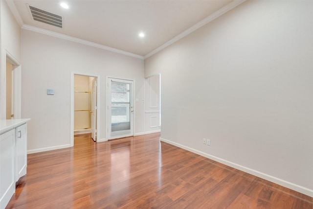 spare room with ornamental molding and light hardwood / wood-style flooring