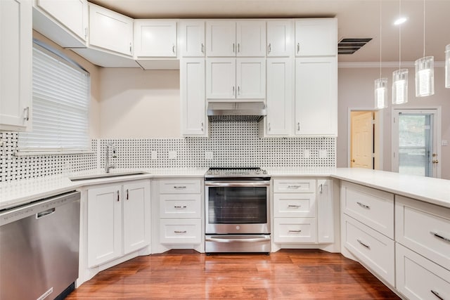 kitchen with pendant lighting, sink, white cabinetry, stainless steel appliances, and ornamental molding