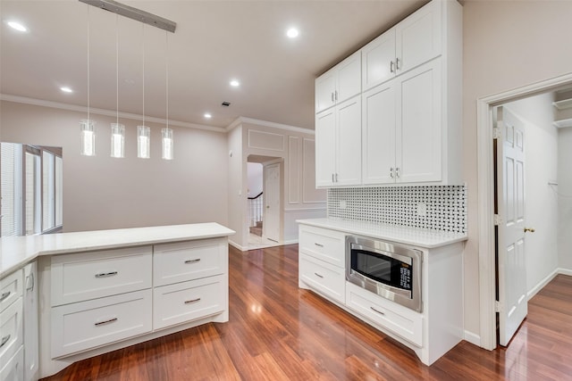 kitchen with white cabinetry, stainless steel microwave, dark wood-type flooring, and pendant lighting