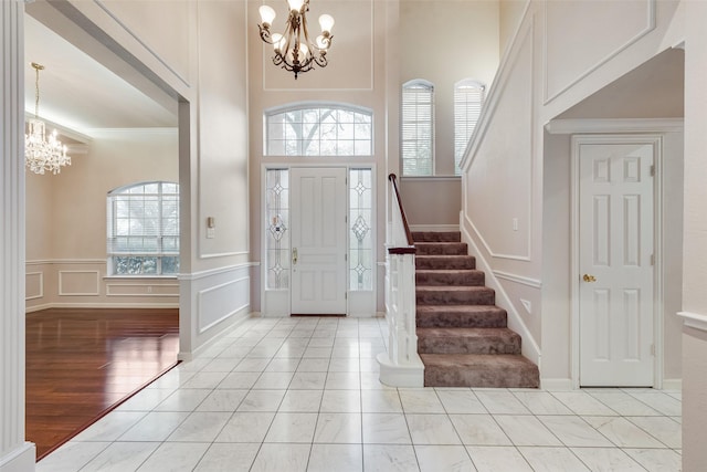 foyer entrance with ornamental molding, light hardwood / wood-style floors, a chandelier, and a high ceiling