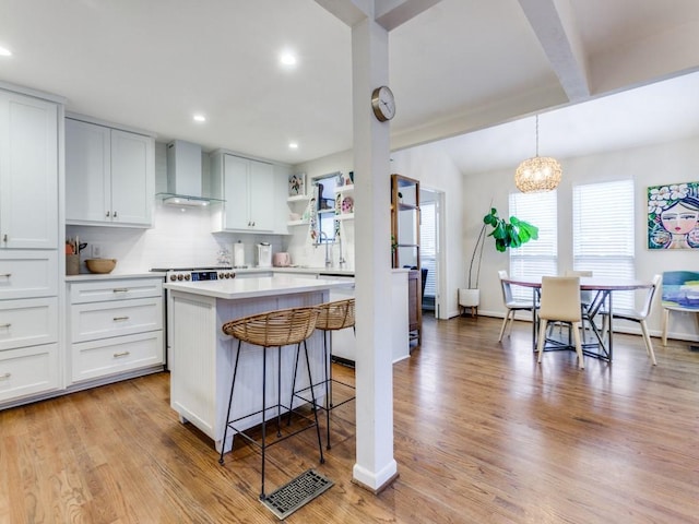 7010 San Mateo Blvd, Dallas, TX 75223 - kitchen featuring wall chimney range hood, open shelves, a center island, light countertops, and a kitchen breakfast bar