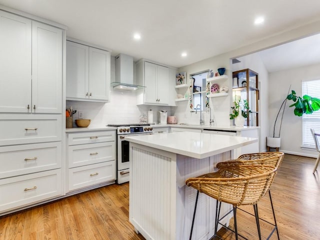 7010 San Mateo Blvd, Dallas, TX 75223 - kitchen featuring wall chimney exhaust hood, high end stainless steel range oven, a breakfast bar, tasteful backsplash, and open shelves