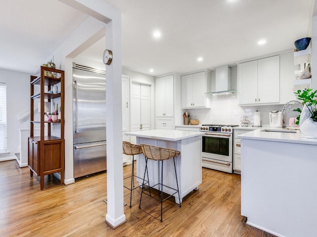 7010 San Mateo Blvd, Dallas, TX 75223 - kitchen featuring premium appliances, wall chimney exhaust hood, a sink, a kitchen breakfast bar, and a center island