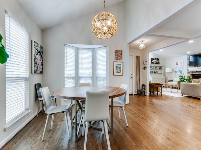 7010 San Mateo Blvd, Dallas, TX 75223 - dining room featuring wood finished floors, a chandelier, baseboards, high vaulted ceiling, and a stone fireplace