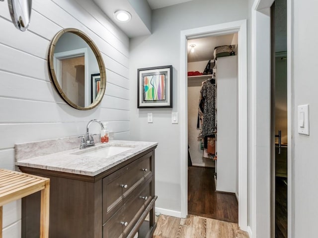 7010 San Mateo Blvd, Dallas, TX 75223 - bathroom featuring wood finished floors, vanity, a spacious closet, and baseboards