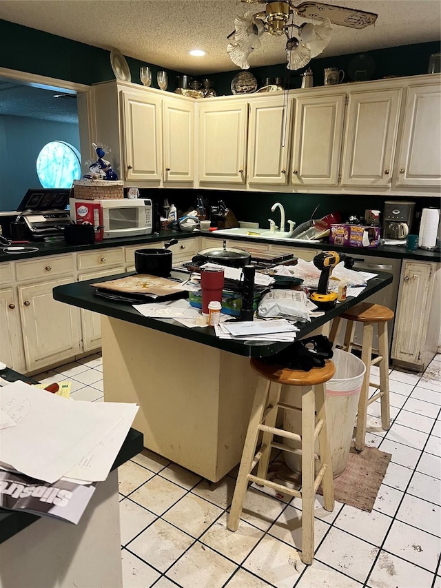 kitchen featuring light tile patterned floors, a textured ceiling, a kitchen island, and cream cabinetry