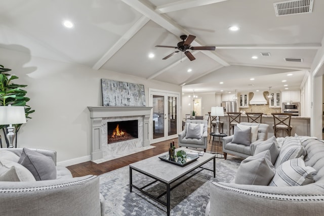 living room with a fireplace, vaulted ceiling with beams, dark hardwood / wood-style flooring, ceiling fan, and french doors